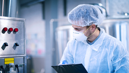 Laboratorijski tehničar u zaštitnoj opremi pregledava uzorak, naglašavajući visoke standarde kvalitete.
