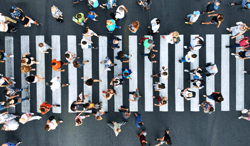 Pogled odozgo na grupu ljudi koji hodaju po pješačkom prijelazu u dvije suprotne kolone, ilustrirajući dinamiku i traženje informacija